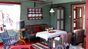 A cozy room with a plaid sofa, a television, a table with a white tablecloth, and a red wall with a plate rack. - 4 Person Holiday Home in Utvik (Stryn)