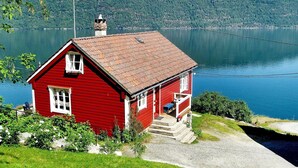 A red house with a chimney, a porch, and a view of a lake and mountains. - 4 Person Holiday Home in Utvik (Stryn)