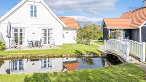 A white house with a red-tiled roof, a small pond, and a white bridge. - 4 Star Holiday Home in Blavand (Blavand)