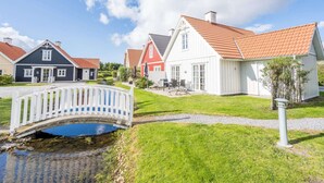A row of houses with a wooden bridge over a small pond. - 4 Star Holiday Home in Blavand (Blavand)