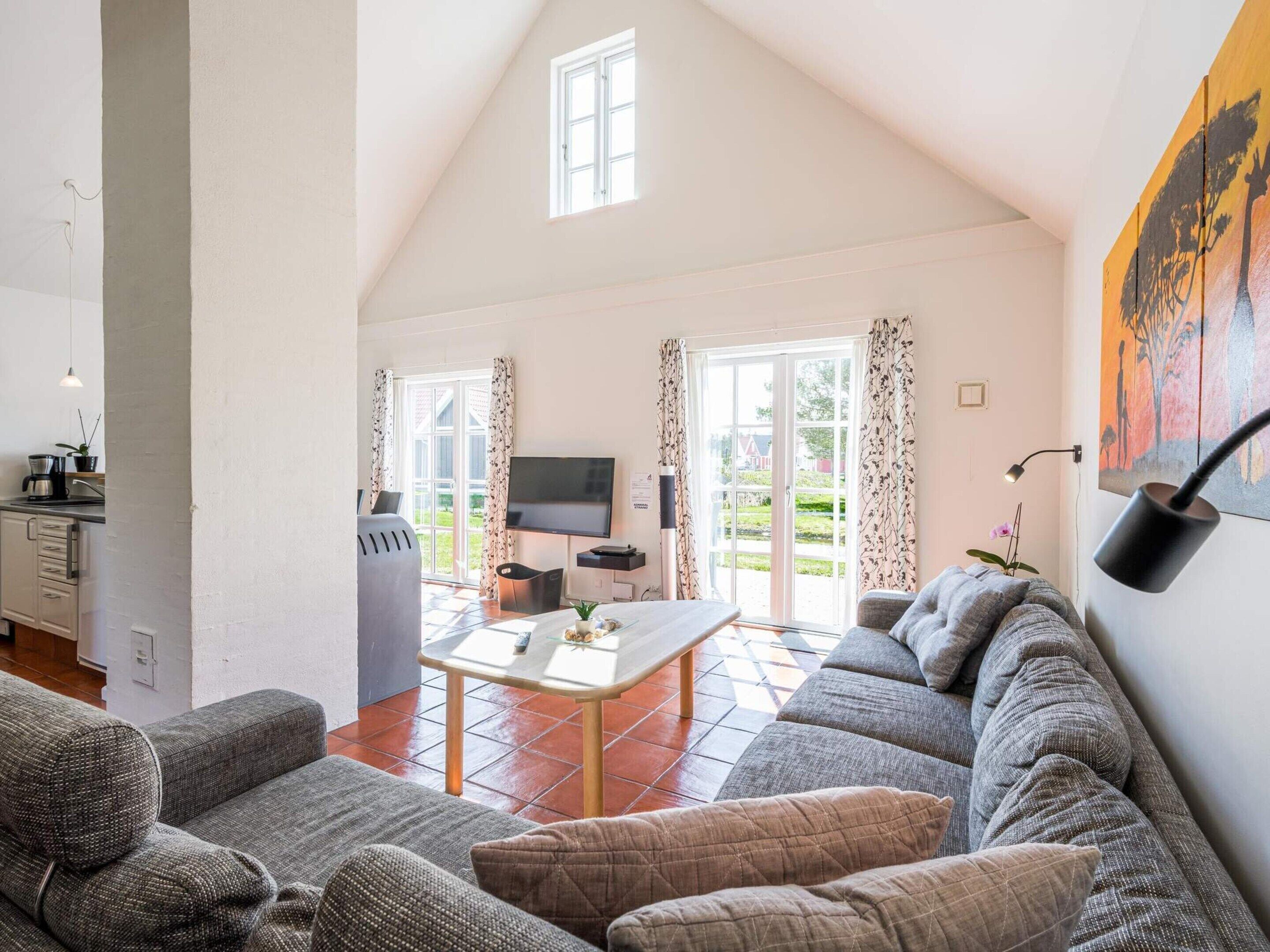 A spacious living area with a sofa set, a television, and a dining table.