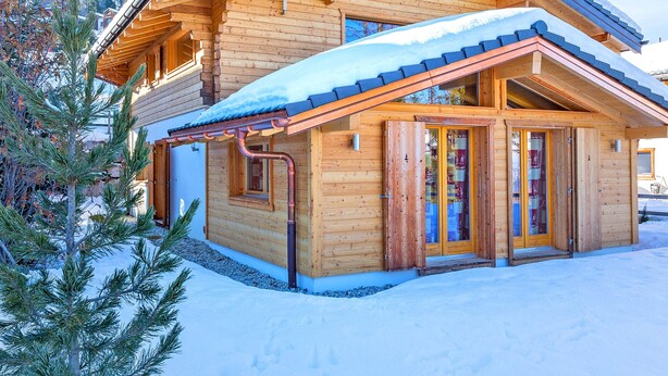 A wooden cabin with a snow-covered roof, a chimney, and a glass door entrance. - Chalet in La Tzoumaz Near Ski Lift (Riddes)