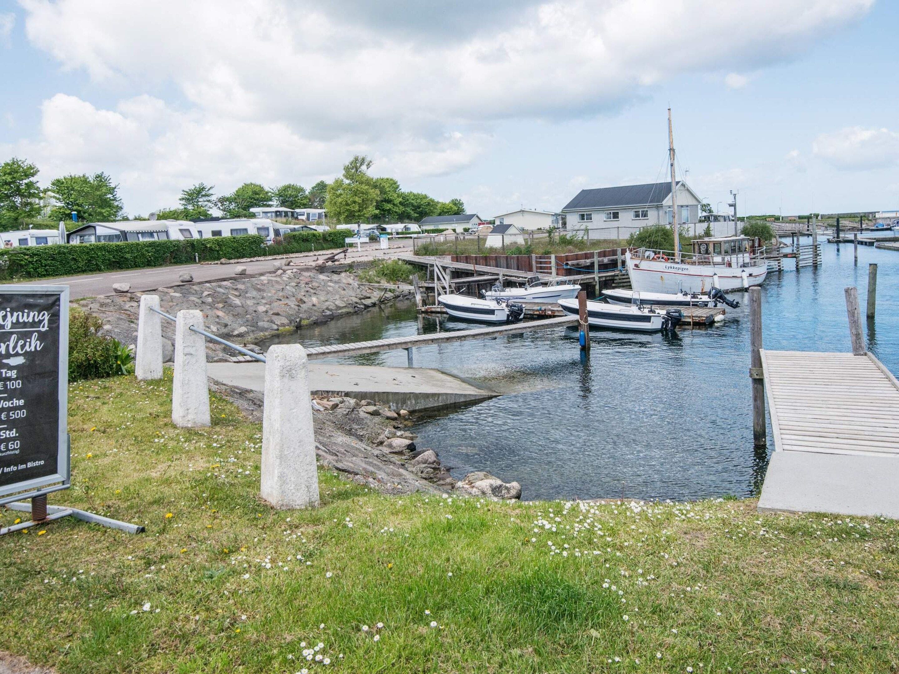 A marina with boats docked, a grassy area with a sign, and a building in the background.
