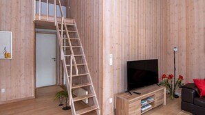 A wooden interior with a TV stand, a sofa, a ladder, and a door leading to another room. - Holiday Home in Sydals (Sydals)
