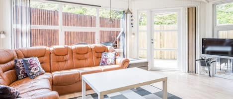 A living room with a leather sofa, a white coffee table, and a television.