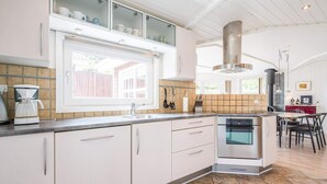 Una cocina moderna con horno empotrado, cafetera y ventana con vistas a una terraza.