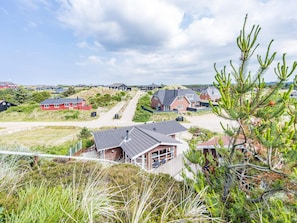 Une zone résidentielle côtière avec des maisons, un chemin de terre et un ciel dégagé.