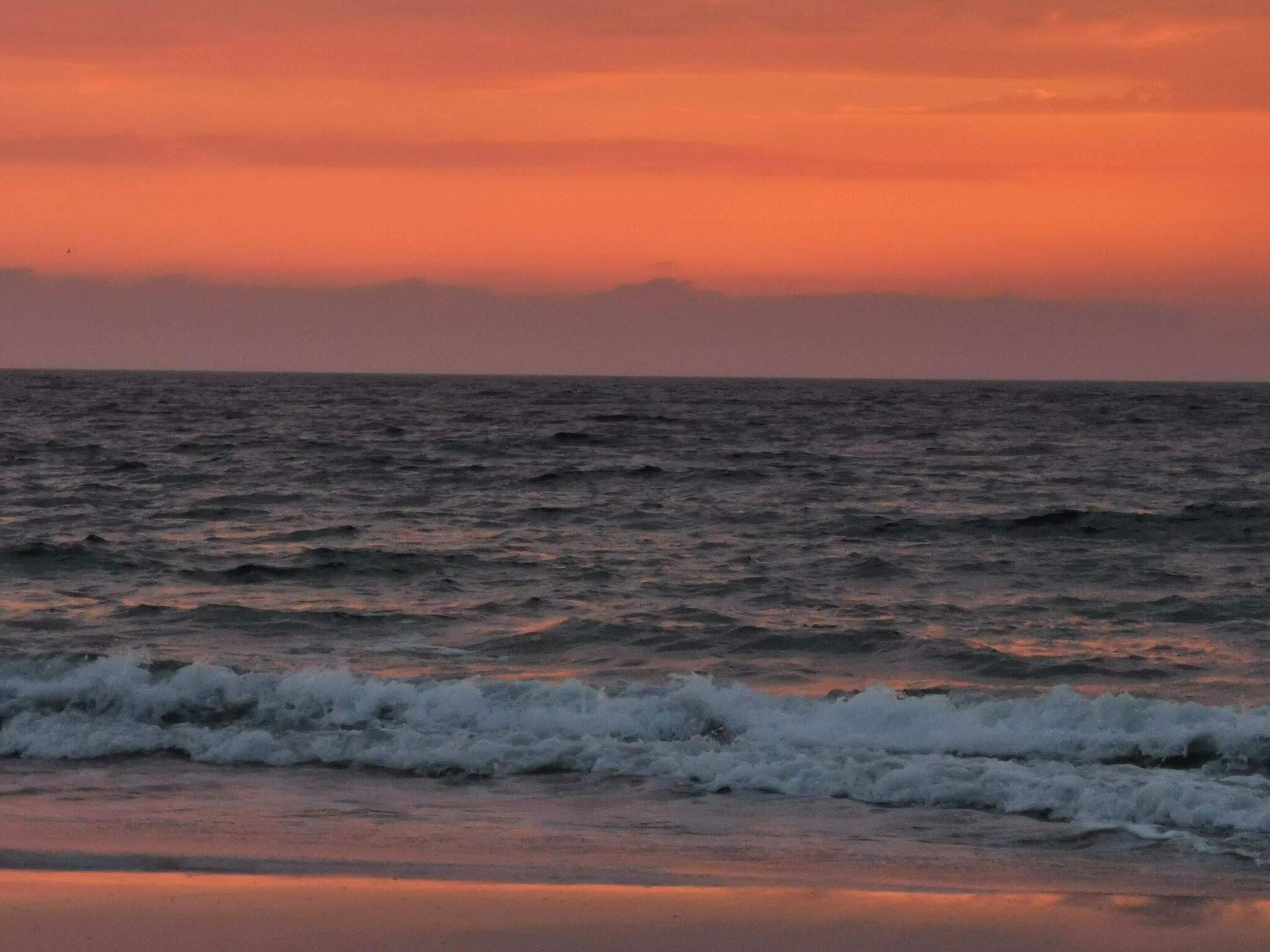Una spiaggia con le onde al tramonto.