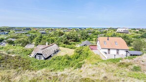 Un pueblo costero con casas rodeadas de vegetación y una vista despejada del mar.