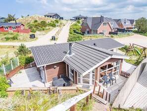 Een kustpand met een terras, buitenmeubels en uitzicht op het strand.