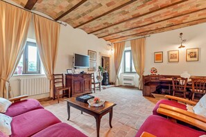 A cozy living room with a fireplace, wooden furniture, and a television. - Rustic Farmhouse in Lazio (Castiglione in Teverina)