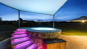 An outdoor hot tub with a stone exterior and illuminated steps.