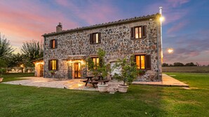A stone building with a patio area, outdoor seating, and a well-lit entrance.
