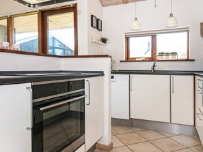 A kitchen with white cabinets, a black countertop, and a window with a view.