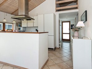 A modern kitchen with white cabinets, a stainless steel range hood, and a microwave.