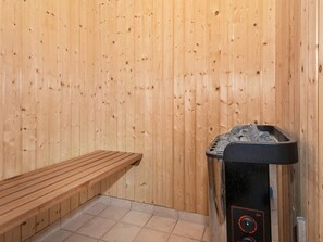 Un sauna avec des murs en bois, un banc et un appareil de sauna.