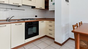 A compact kitchen with white cabinets, a black stove, and a wooden countertop. - Vibrant Holiday Home in Lazise with Swimming Pool near 2 Lakes (Lazise)