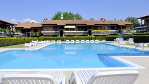 A swimming pool with white lounge chairs and a building with multiple balconies in the background. - Vibrant Holiday Home in Lazise with Swimming Pool near 2 Lakes (Lazise)