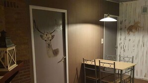 Un coin repas avec une table et des chaises, une porte ornée d’une tête de cerf et une décoration murale représentant un léopard.
