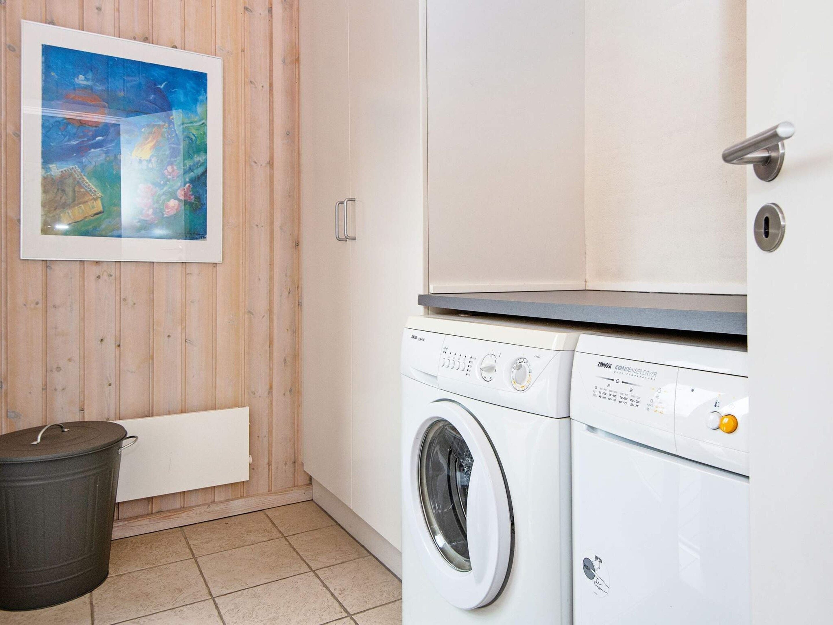 A laundry room with a washing machine, a drying machine, and a trash bin.