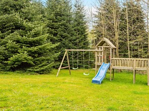 A playground with a swing set and a slide, surrounded by dense trees. - Holiday Home in Sydals (Sydals)