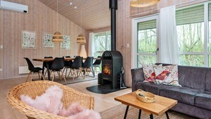 Ein gemütliches Wohnzimmer mit Kamin, einer Couch, einem Essbereich und großen Fenstern.