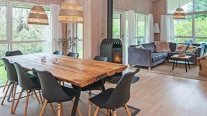 Ein geräumiger Raum mit einem großen Holztisch, schwarzen Stühlen, einer Couch und einem Kamin.