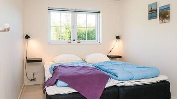 Un dormitorio con cama, lámparas de noche, ventana y una obra de arte en la pared.