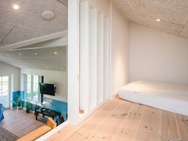 Una habitación con piso de madera, una cama, un televisor y una ventana con vista a follaje.