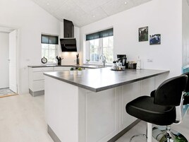 Una cocina moderna con una isla grande, armarios blancos y una silla negra.