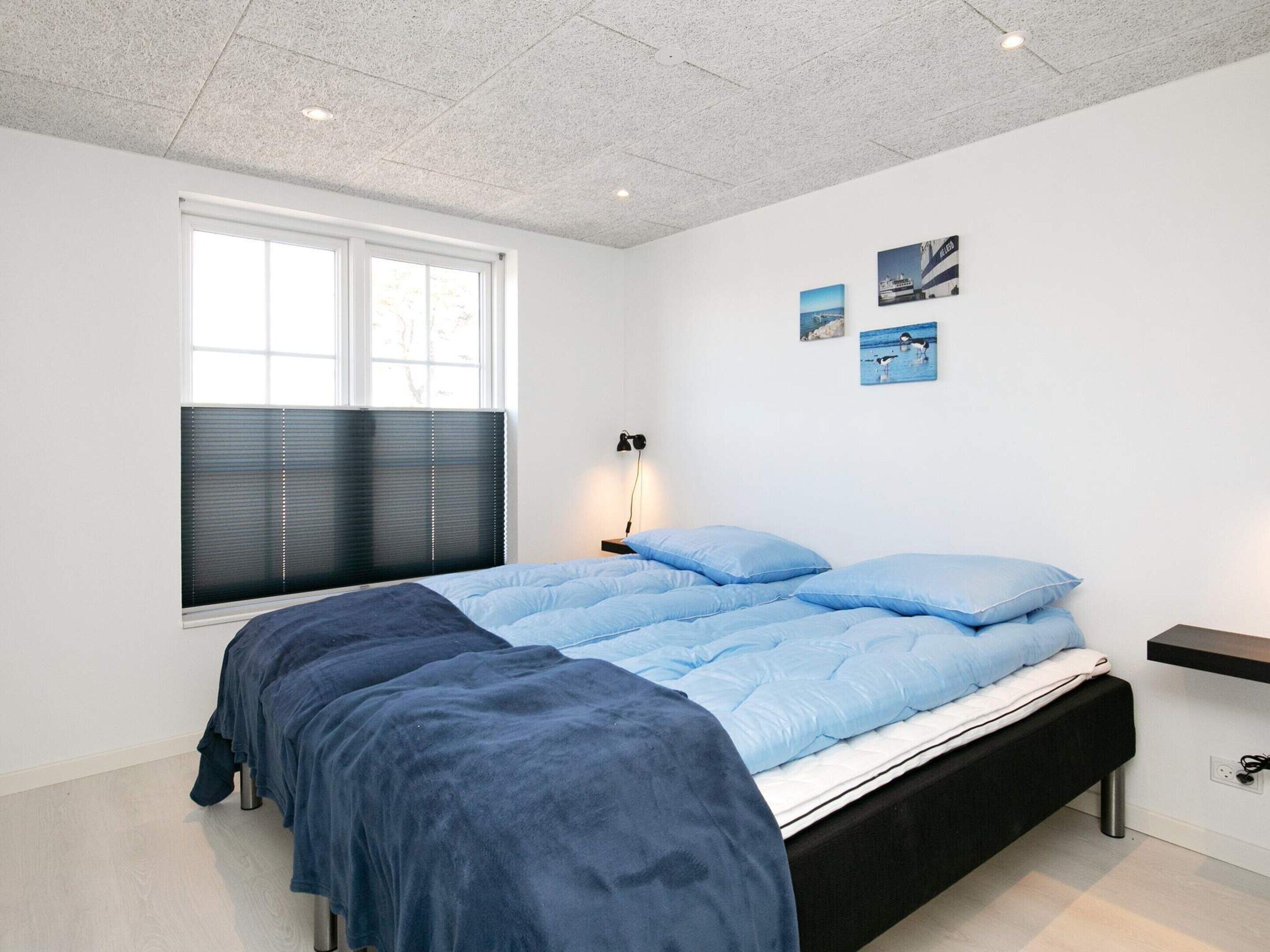 Un dormitorio moderno con una cama grande, una ventana con persianas, una mesita de noche y decoración en la pared.