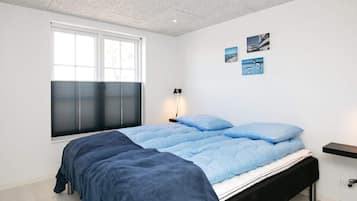 Un dormitorio moderno con una cama grande, una ventana con persianas, una mesita de noche y decoración en la pared.