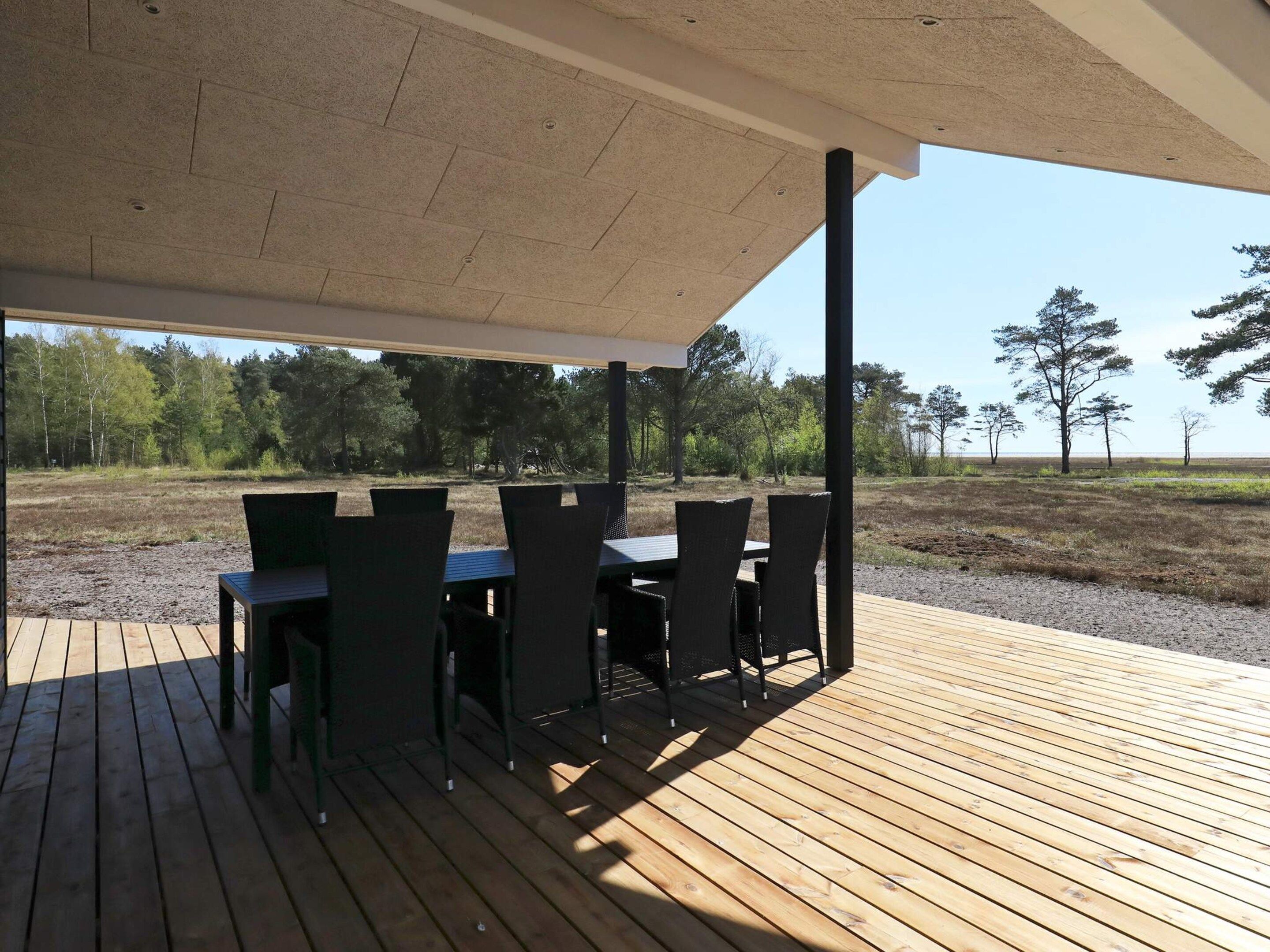 An outdoor patio with a table and chairs, a covered area, and a view of a natural landscape.