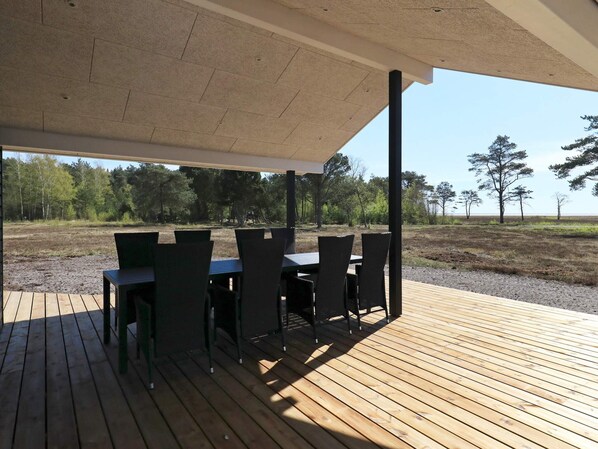 An outdoor patio with a table and chairs, a covered area, and a view of a natural landscape.