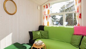 A cozy room with a green sofa, a small wooden table, and a green suitcase. - 6 Person Holiday Home in Gilleleje-by Traum (Gilleleje)