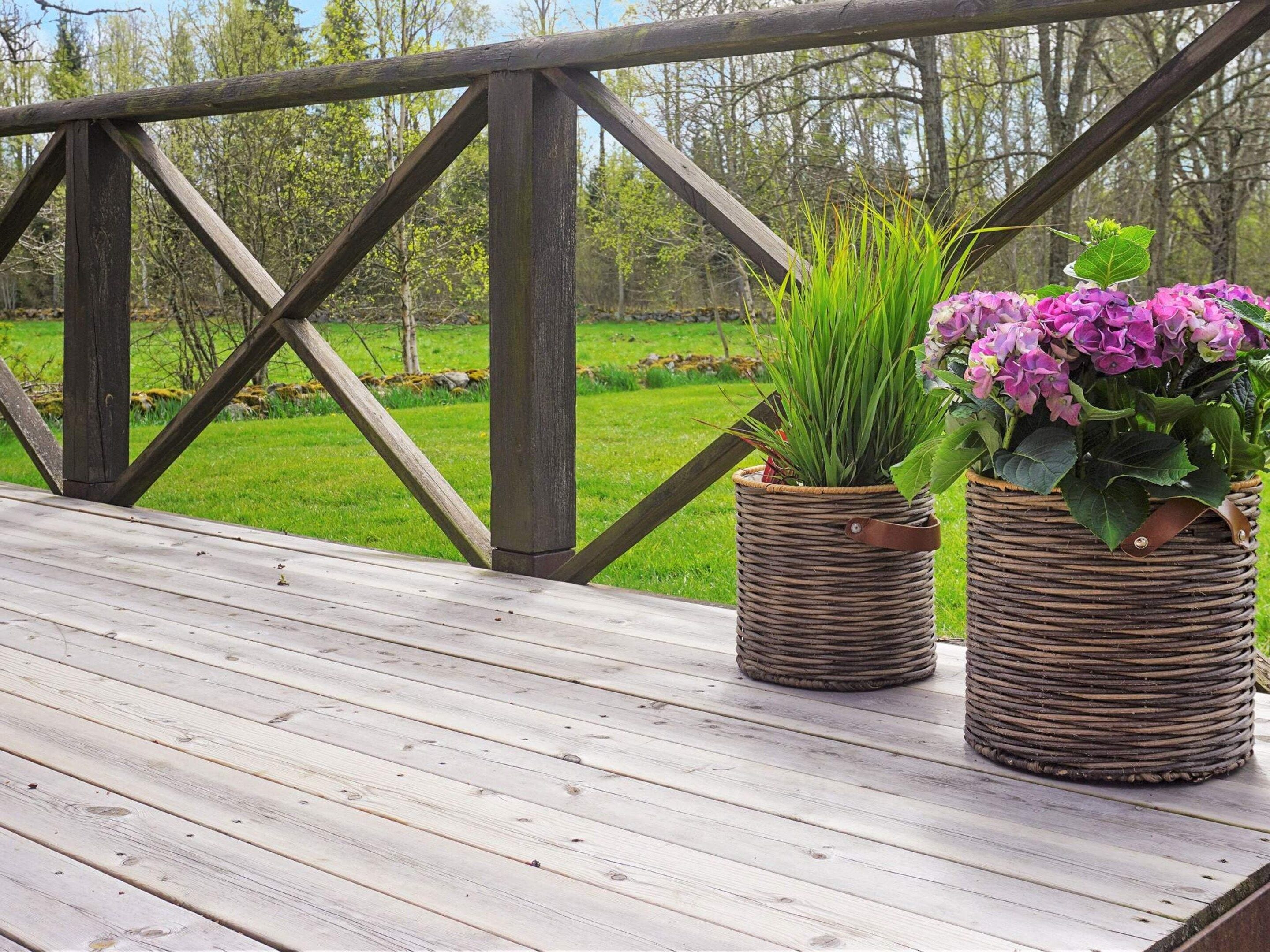 A wooden deck with two woven planters containing plants.