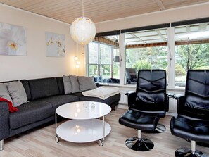 A modern living room with a grey sofa, a white coffee table, and two black leather chairs.