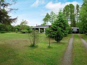 A house with a covered porch, a gravel driveway, and a forested area. - 6 Person Holiday Home in Vaeggerlose (Vaeggerlose)