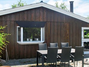 Un bâtiment en bois doté d’une fenêtre et d’un espace patio avec une table et des chaises.