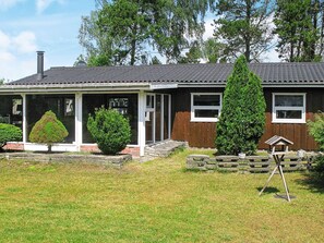 A single-story house with a covered porch, a chimney, and a well-maintained lawn. - 6 Person Holiday Home in Vaeggerlose (Vaeggerlose)