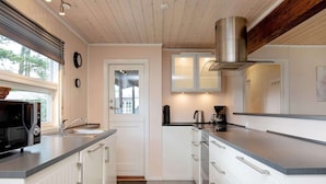 A modern kitchen with white cabinetry, a stainless steel range hood, and a window with blinds. - 6 Person Holiday Home in Vaeggerlose (Vaeggerlose)
