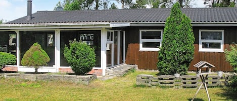 Ein zweistöckiges Haus mit einer Veranda, einem Schornstein und einem gepflegten Rasen.
