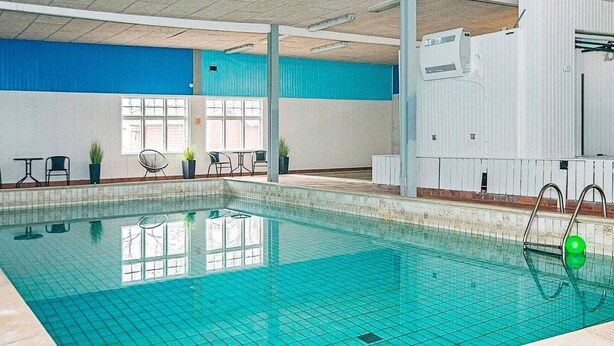 An indoor swimming pool with clear blue water, tiled walls, and a few potted plants. - 12 Person Holiday Home in Hojer (Højer)
