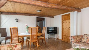 A cozy living room with wooden furniture, a television, and a door leading to another room. - 12 Person Holiday Home in Hojer (Højer)