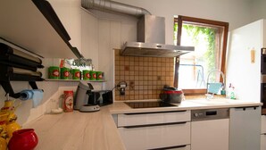 Une cuisine moderne équipée d’un lave-vaisselle intégré, d’une machine à café et d’une fenêtre donnant sur un espace verdoyant.