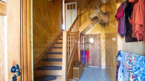 Un escalier en bois mène au deuxième étage, où une tête de cerf est accrochée au mur.