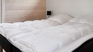 A bed with a white duvet in a room with wooden panel walls. - Holiday Home in Hadsund (Hadsund)