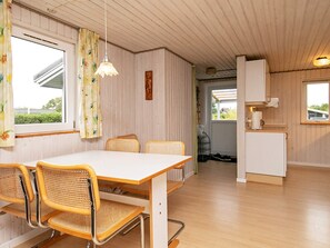 A room with a wooden table and chairs, a white cabinet, and a window with curtains.