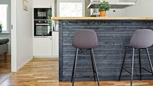 A modern kitchen with a wooden island, two bar stools, and a potted plant. - 4 Star Holiday Home in Loftahammar (Loftahammar)