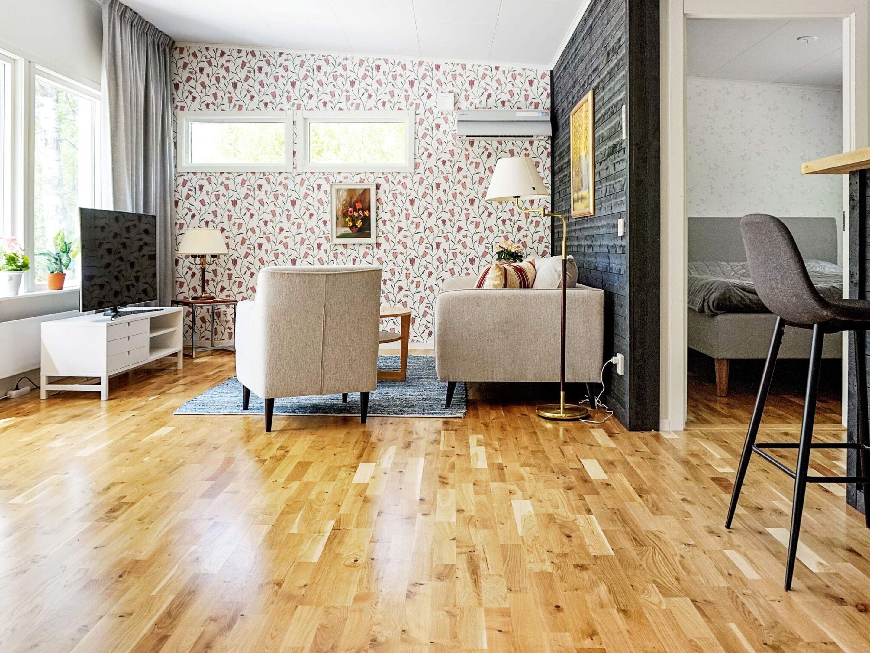 Una sala de estar moderna con piso de madera, un sofá, una silla, un televisor y un escritorio.